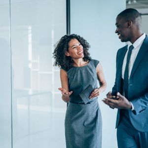 Shot of two young colleagues having a discussion in modern office. Confident young business people working together in the office. Corporate business persons discussing new project and sharing ideas in the workplace.