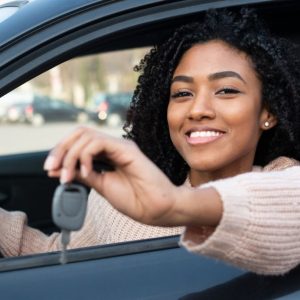 Happy young black woman seated in her new car